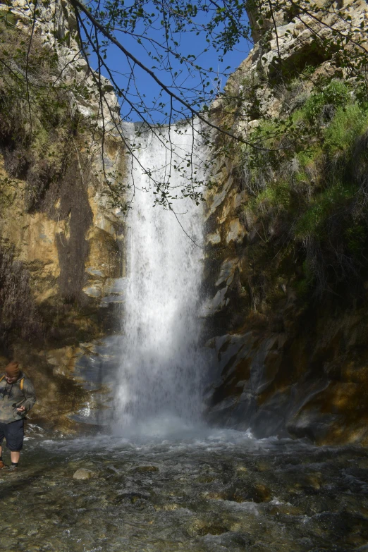 there is a man standing under a large waterfall