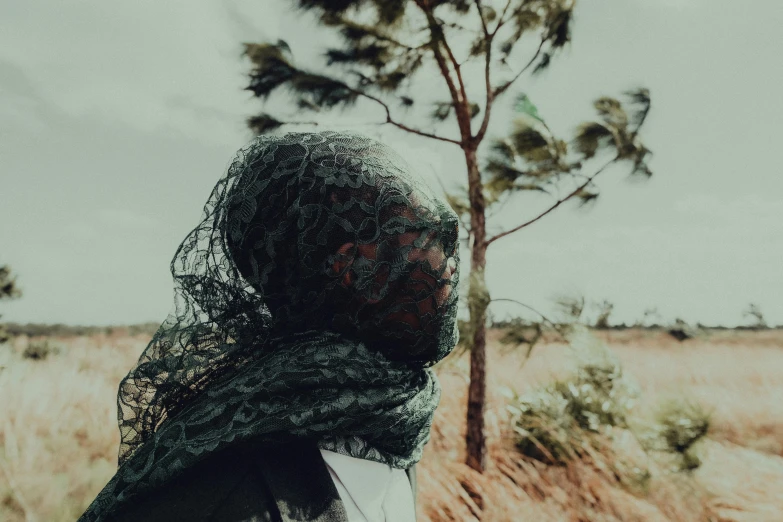 the woman wearing a scarf stands by a tree