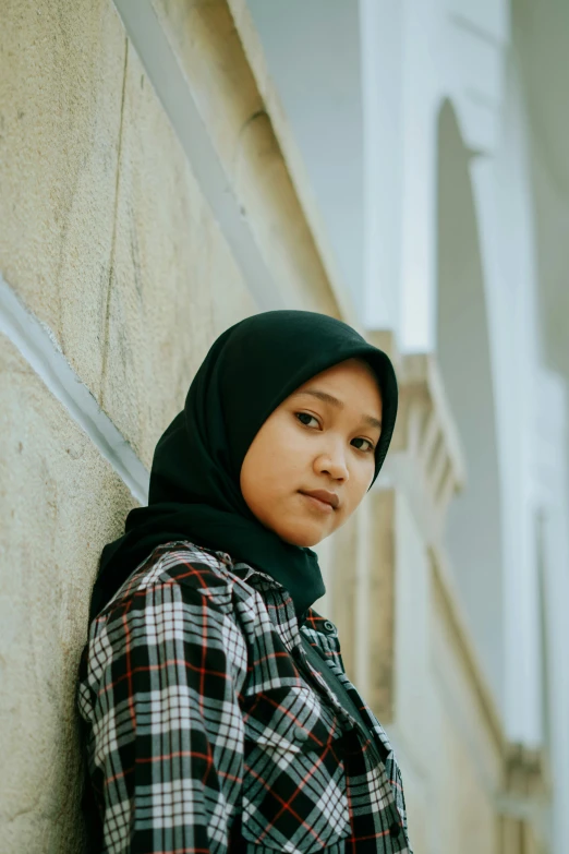 a young person leans against a wall