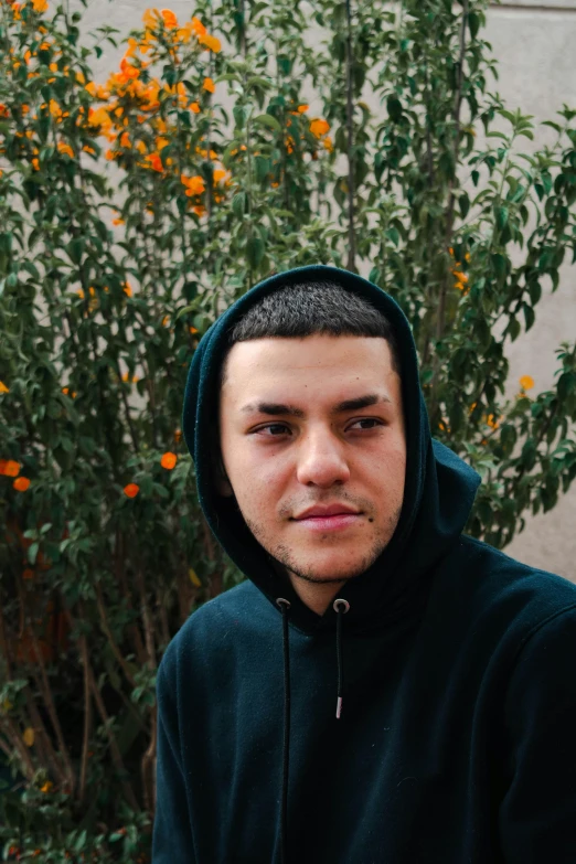 a young man in a hooded sweatshirt poses for the camera