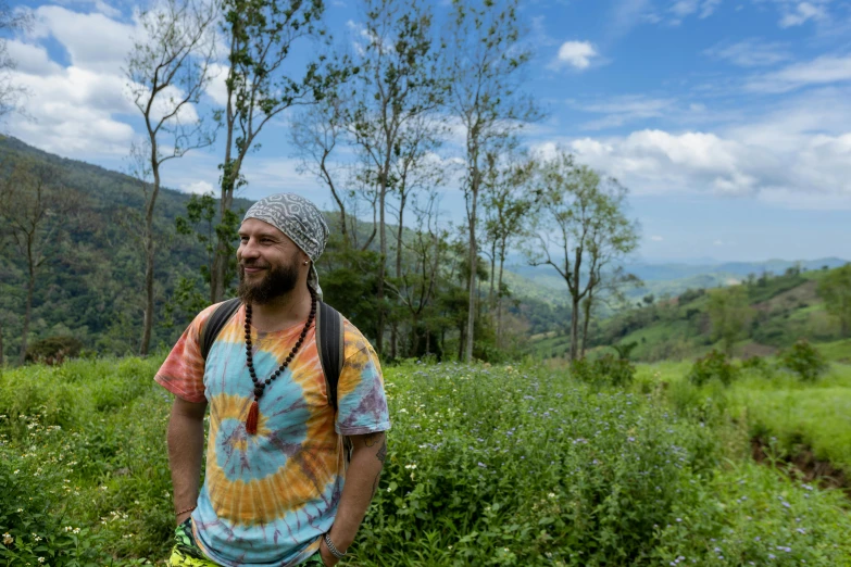 a man in a tie dye shirt in the middle of a green field