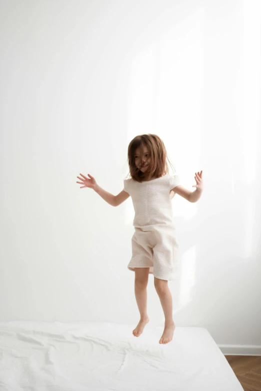 a little girl jumping into the air on a bed