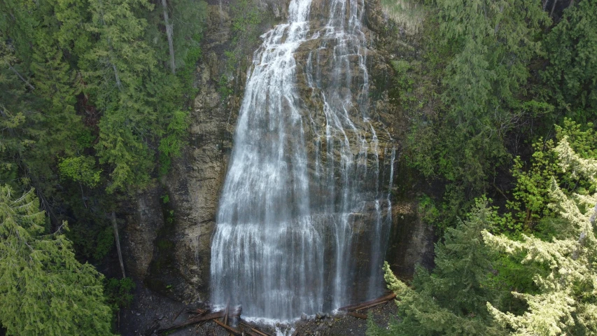 a very tall waterfall surrounded by green trees