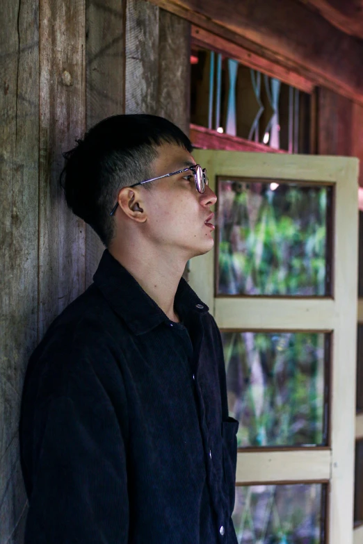 man standing by wooden building wearing metal sunglasses