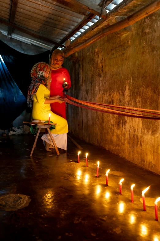 a woman sitting in front of many lit candles