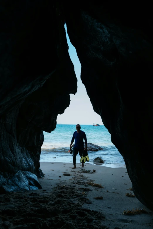 there is a man on the beach walking by the ocean