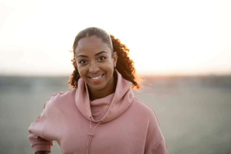 a beautiful woman in pink wearing a hoodie and smiling