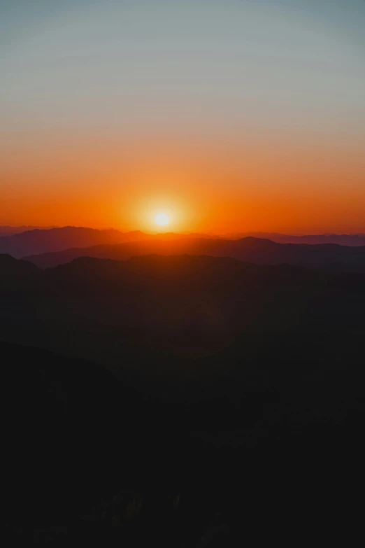 the sun setting over a mountain range from an airplane