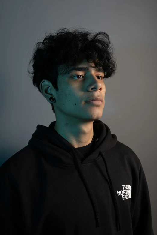 a young man with curly hair in a dark sweatshirt