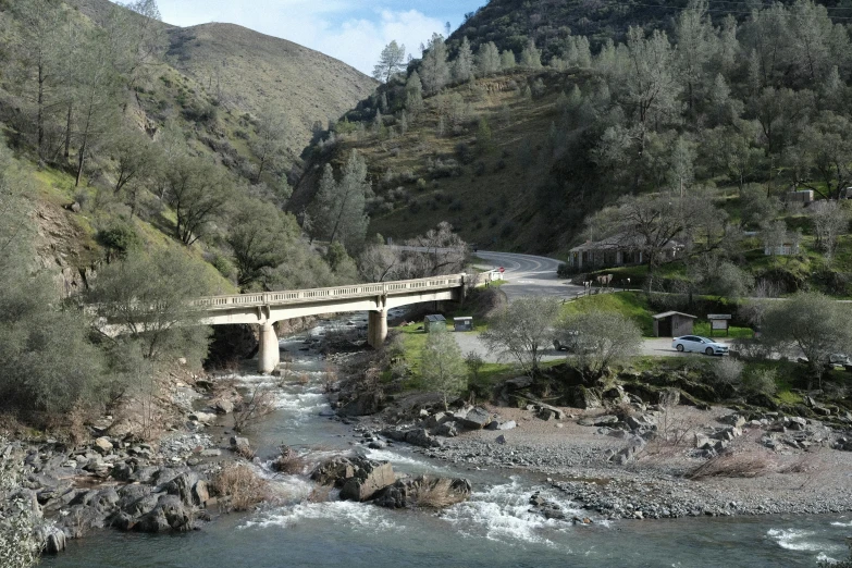 a bridge over a small river next to a lush green mountain side