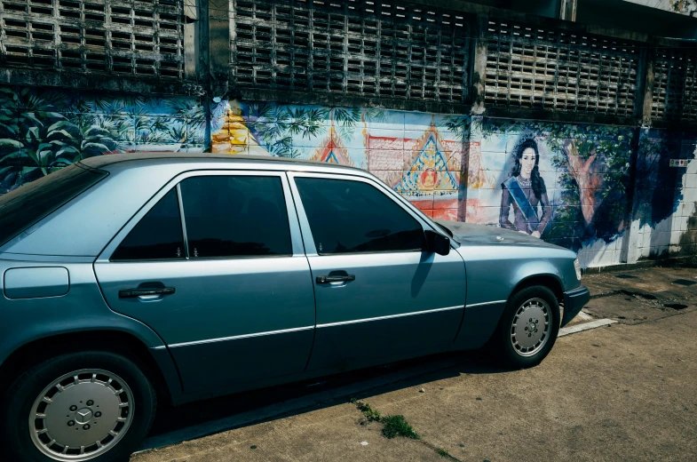 a blue car parked by a colorful wall