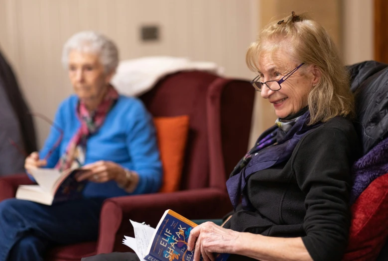 two older women sitting in chairs with books