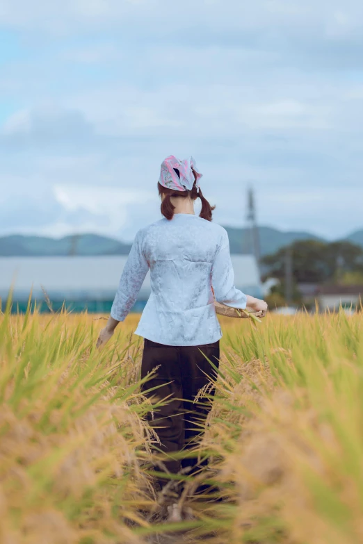 the girl is walking through a large field of tall grass