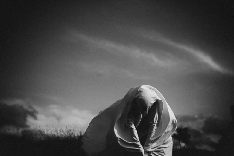 man in white hoodie crouching down to pograph the sky