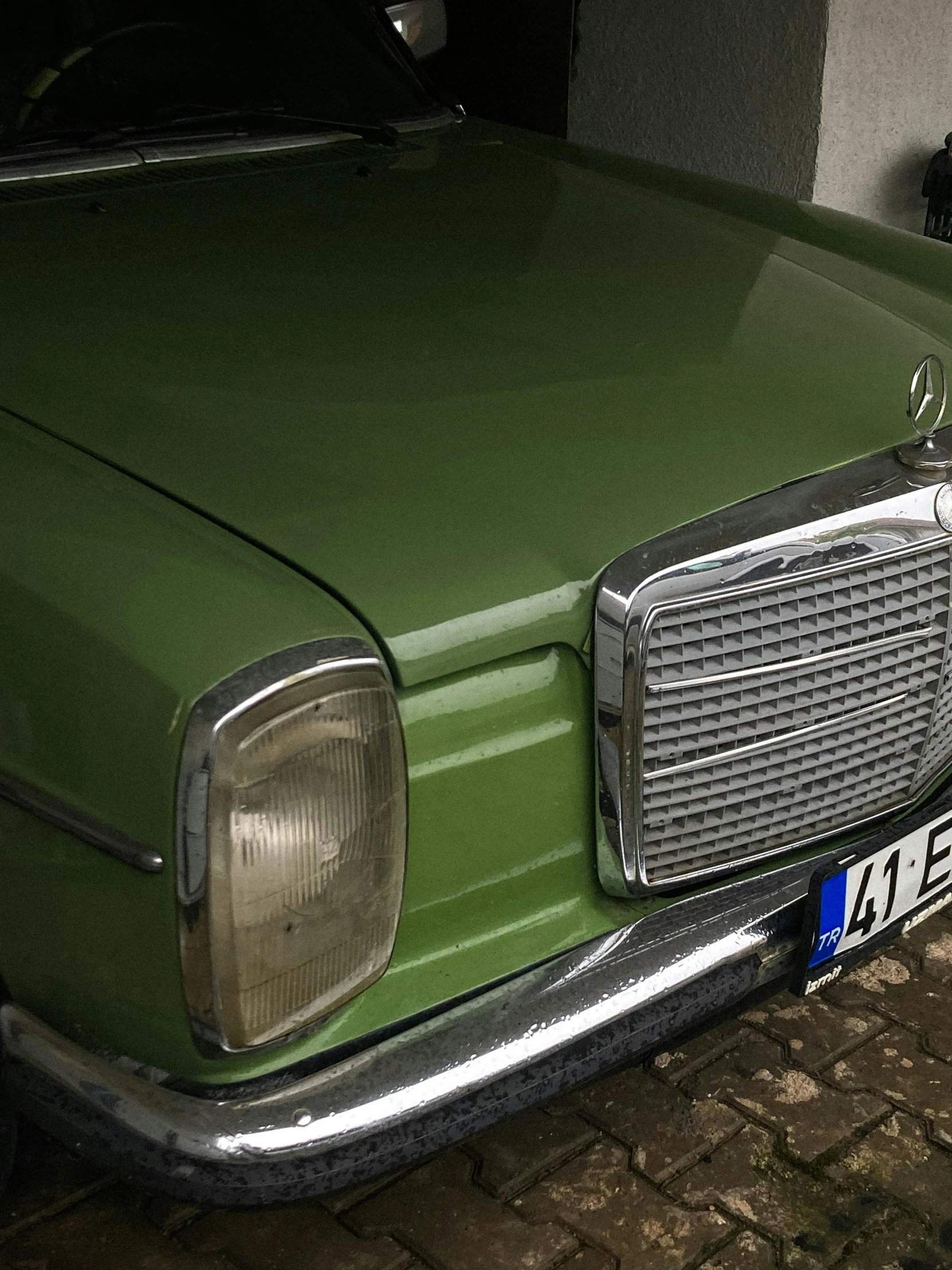 an old, dark green classic mercedes is parked