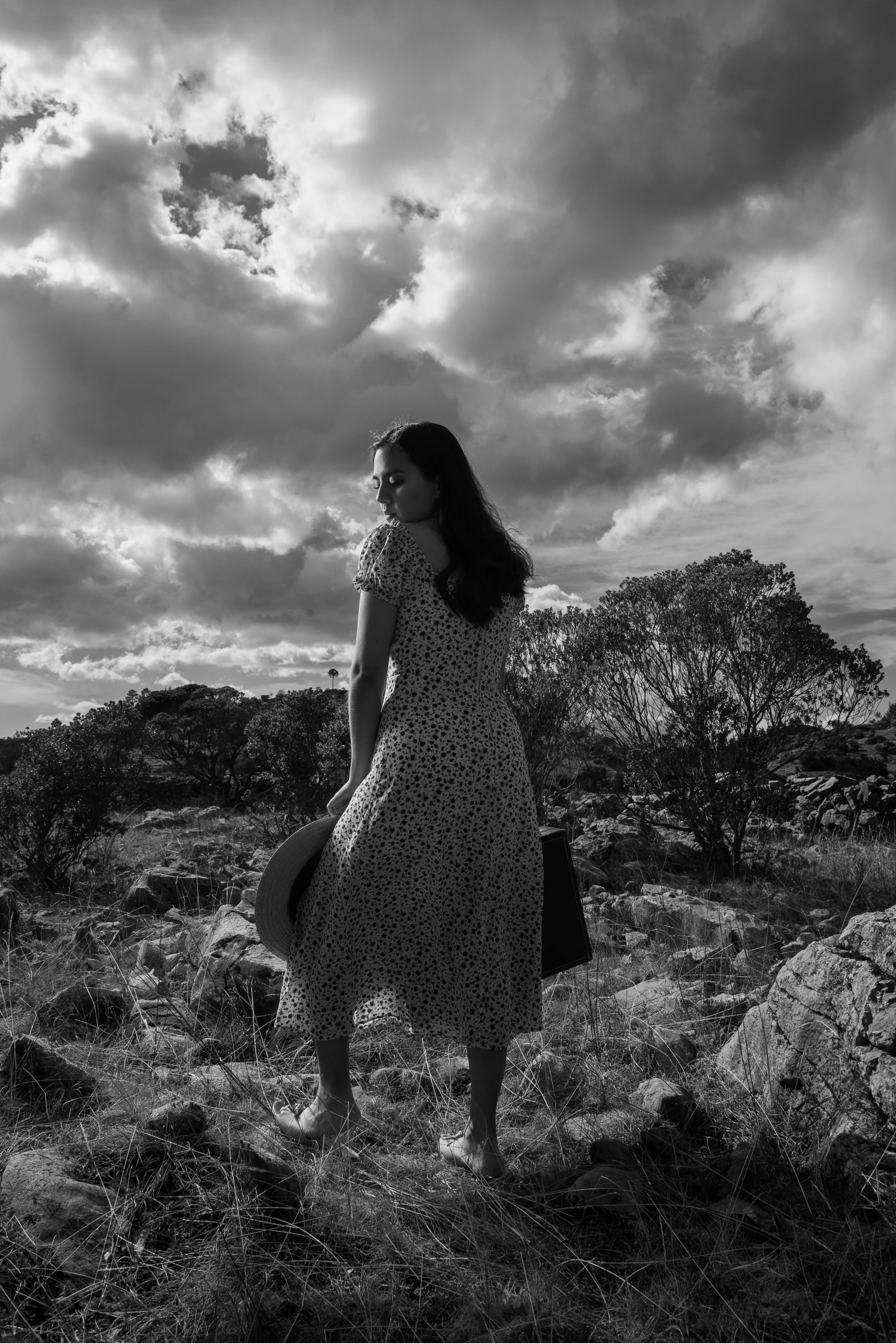 woman walking through open field under cloudy sky