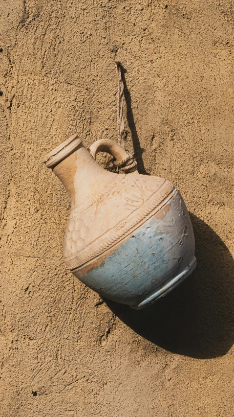 a broken vase lies in the sand and looks up at it