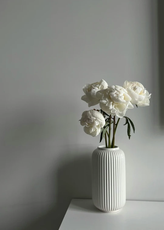 white vase filled with flowers on top of a white table