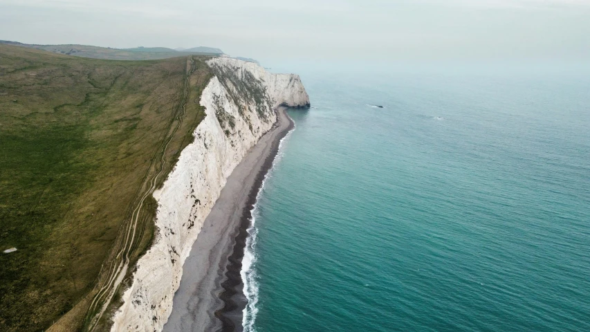 a long cliff is next to a beach on the sea