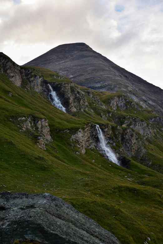 there is a tall mountain with a waterfall and moss