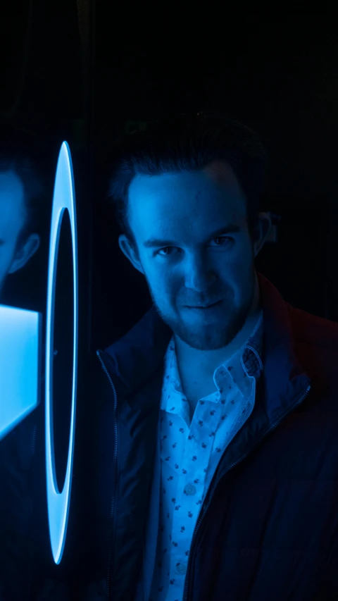 a man smiling next to a large blue object