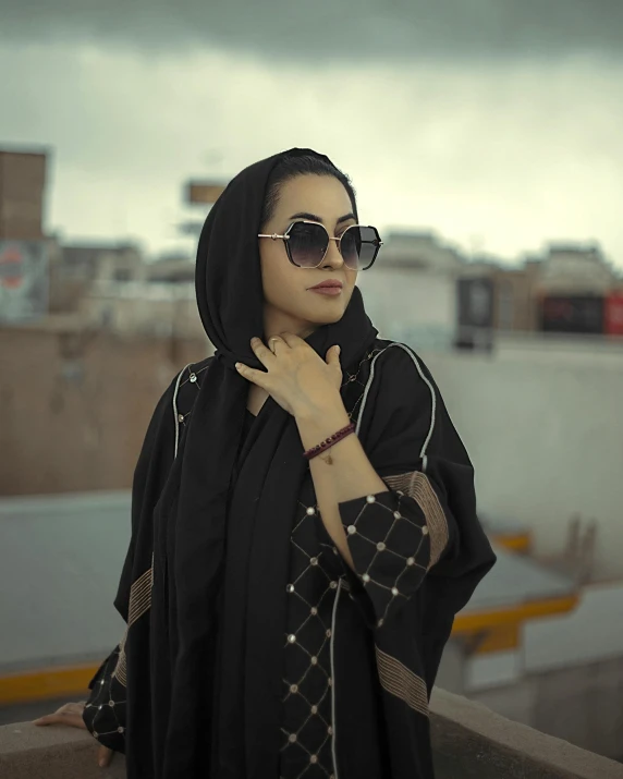 a beautiful young lady wearing sunglasses standing in the street