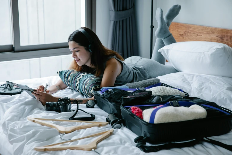 a woman laying on a bed with several travel bags