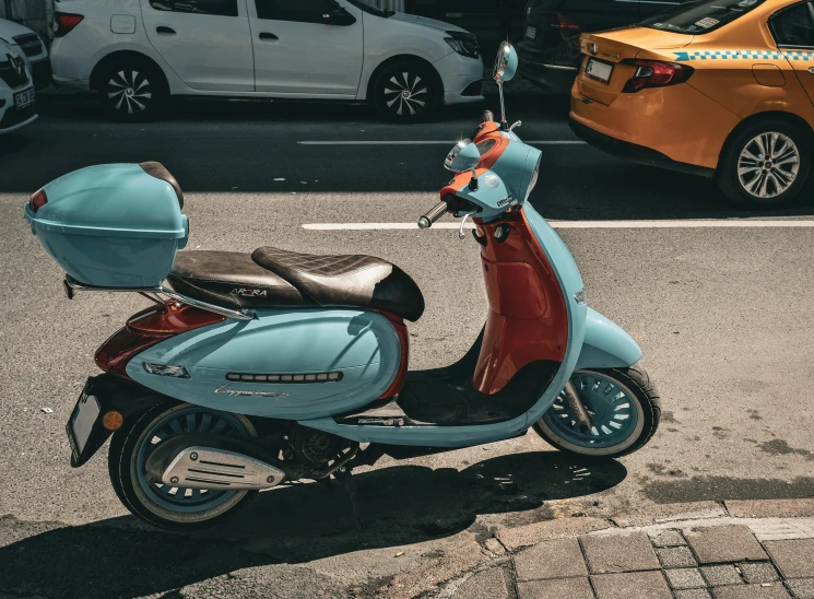 a scooter is parked at the curb next to a car