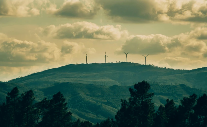 four wind generators on a mountain range at sunset