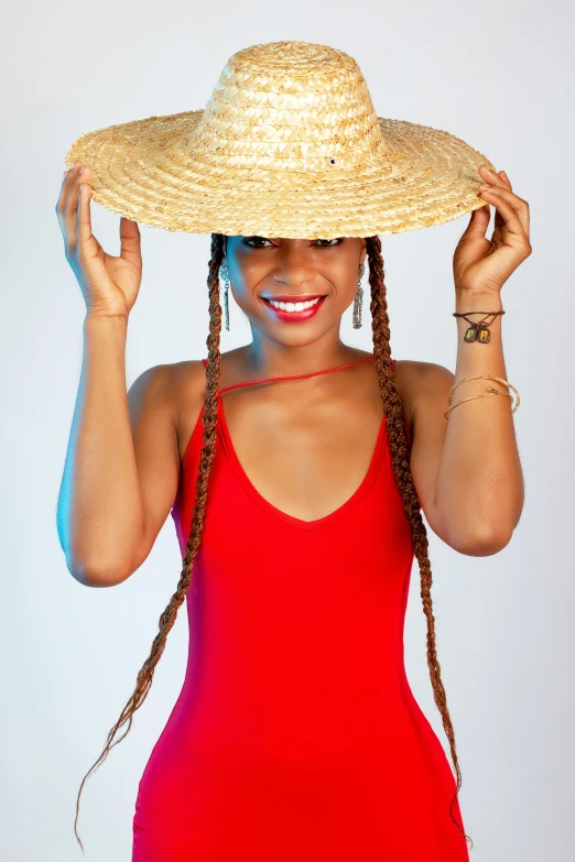 a woman posing for the camera in a red dress and straw hat