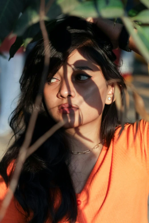 a woman in an orange shirt holding up a plant