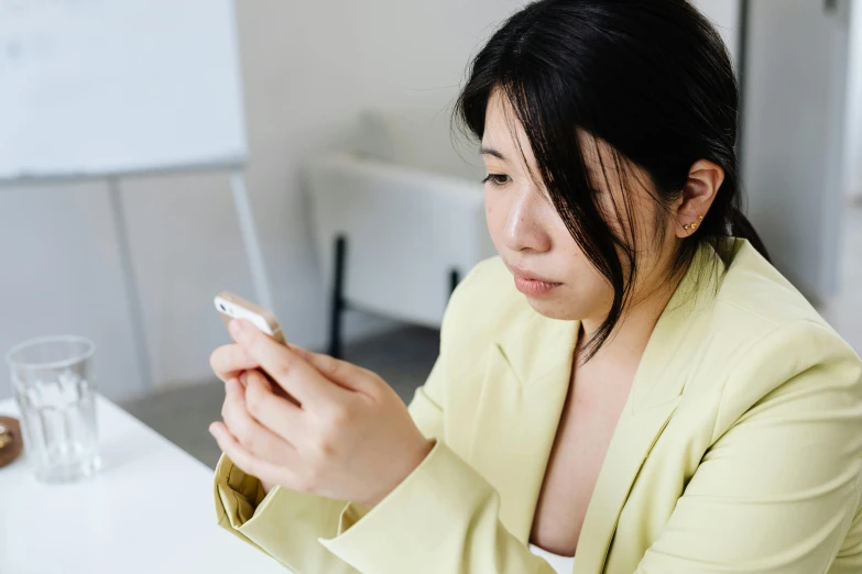 a young woman looks down while holding her phone