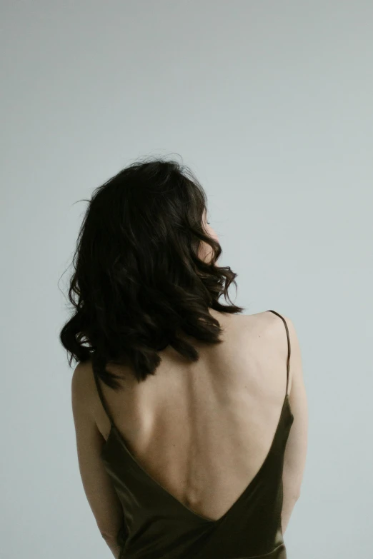 a lady with long dark hair standing in front of a blue background