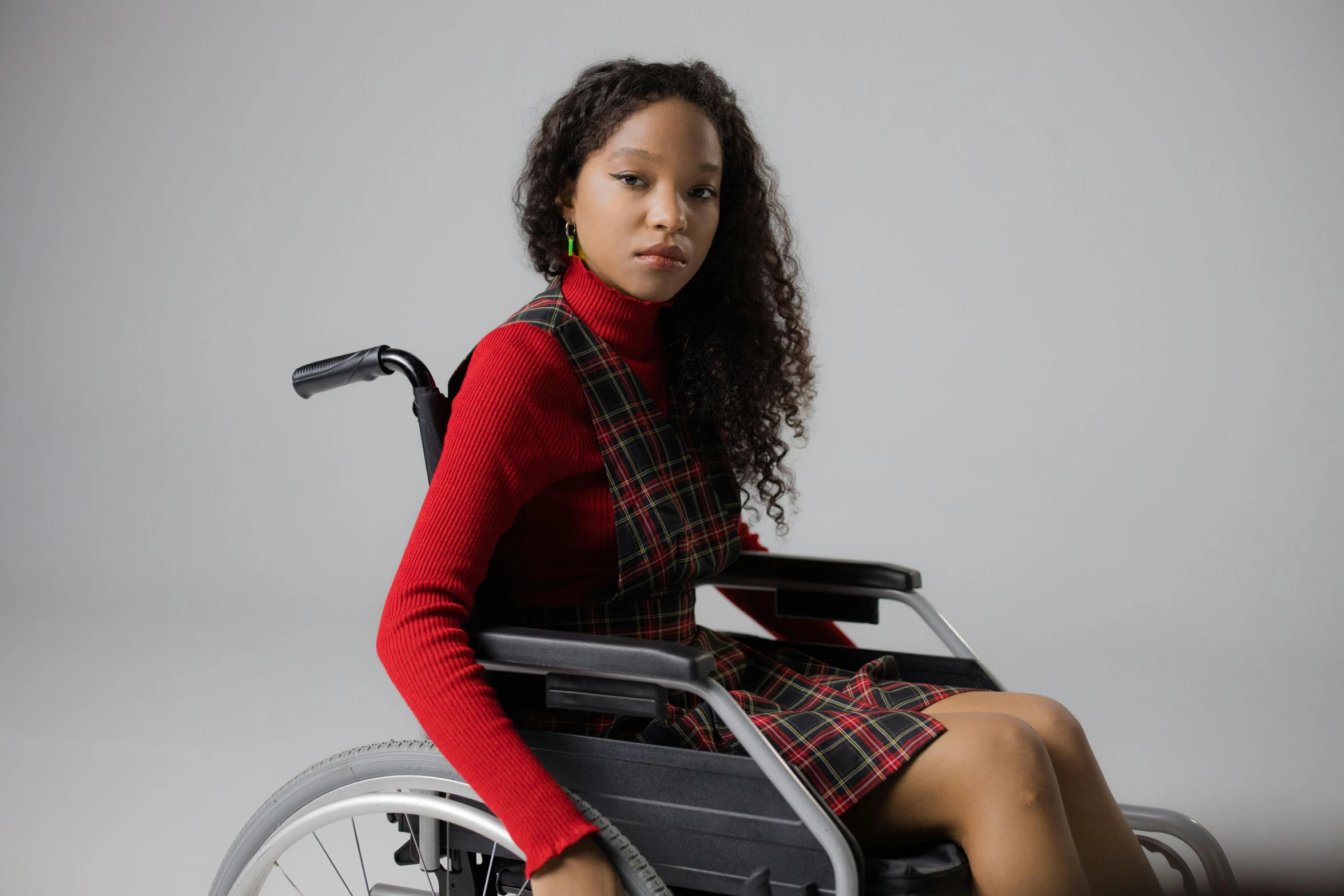 a woman in a red sweater is sitting on a wheel chair