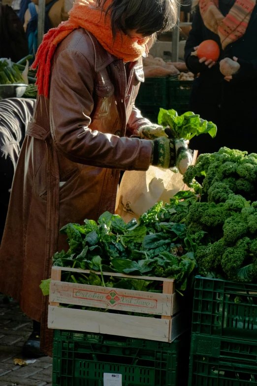 a woman looking at the broccoli she is picking up