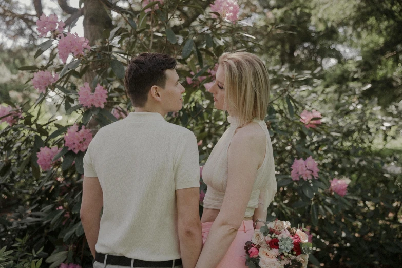 man and woman standing in front of pink flowers