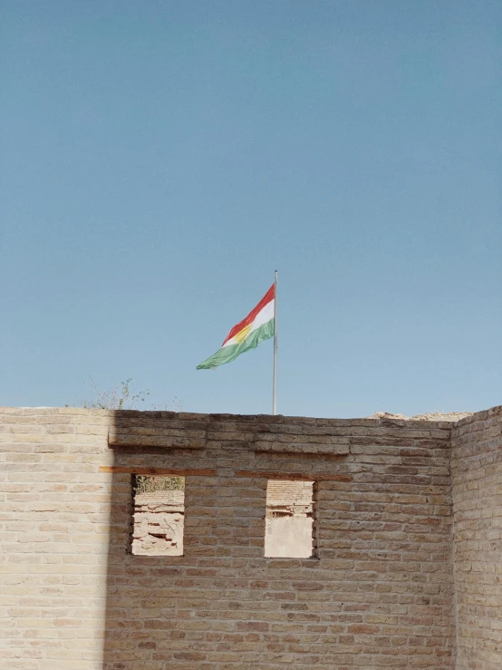 a red white and green flag is flying on top of a building