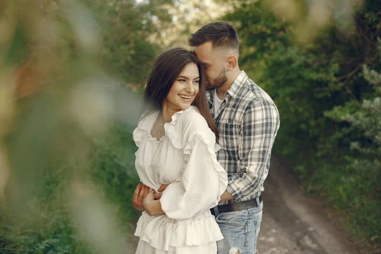 a man and woman pose next to each other in front of trees