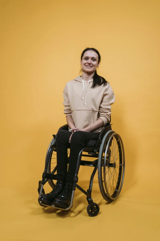 a woman poses in a wheelchair against a yellow background