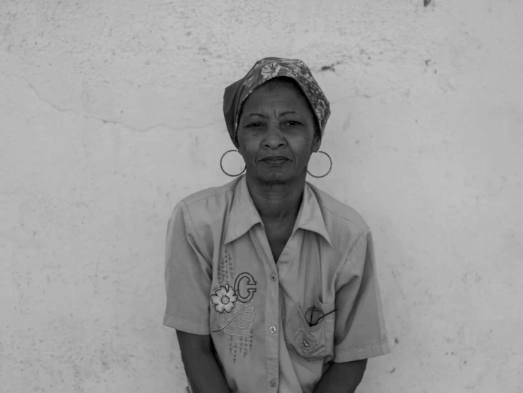 a woman with earrings is standing in front of a wall