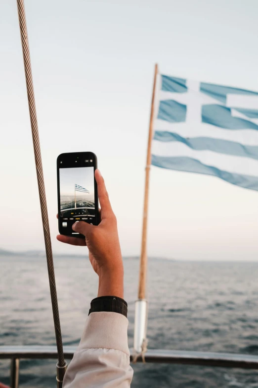 a hand holding up an iphone taking a po of the ocean