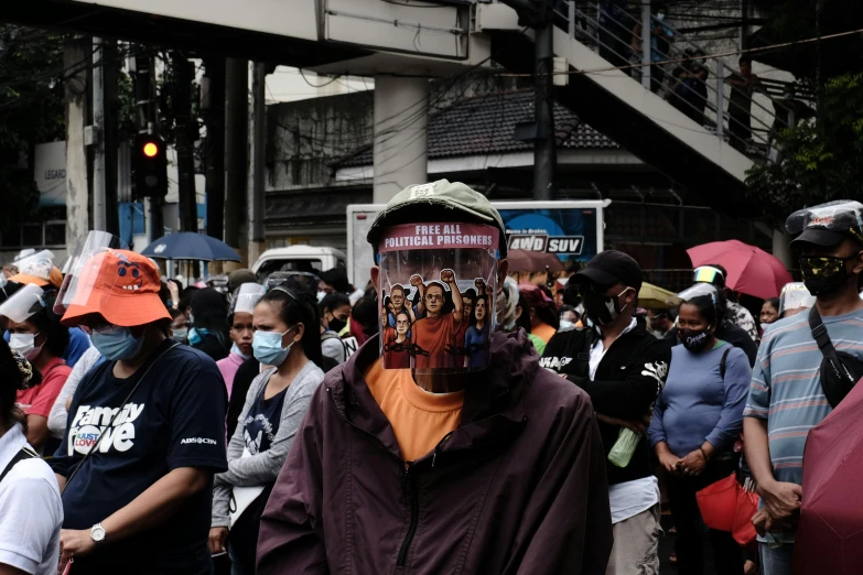 a man with an odd mask walks in front of a crowd