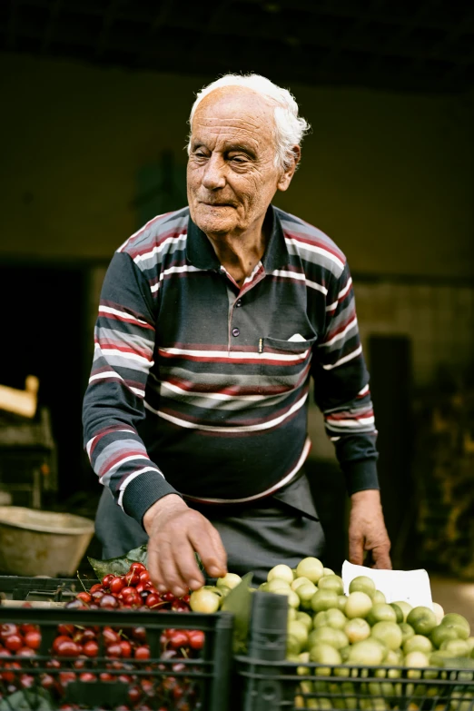 an older man standing behind a crate filled with fruit