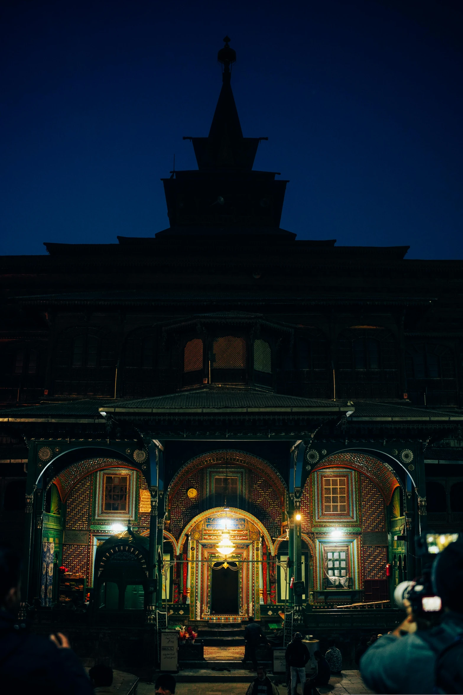 an illuminated church entrance at night with people standing around it