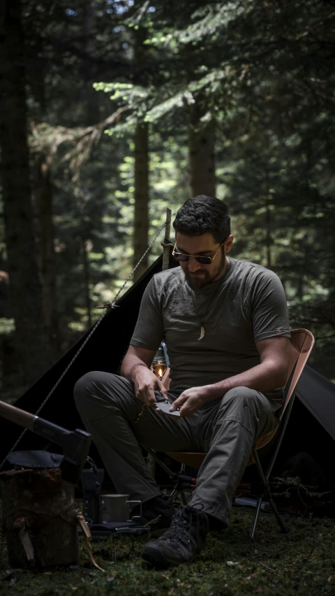 a man sits in his camping chair and holds a bottle of alcohol