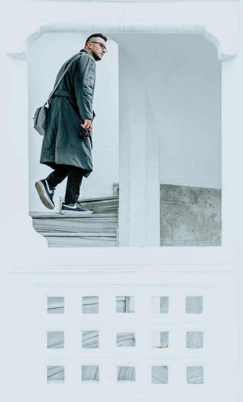 a man in grey and black coat walking down a set of steps