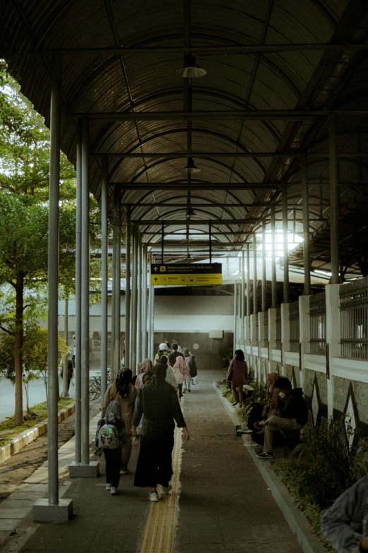 many people are sitting on the benches and walking under an overhang