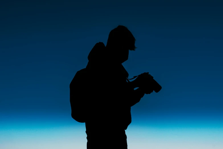 a man in black jacket with camera and dark shadow