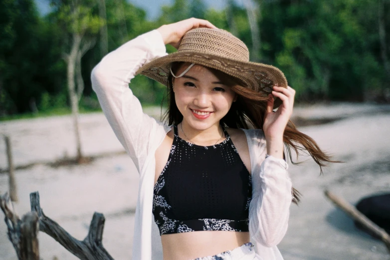 woman wearing a hat on the beach near a tree