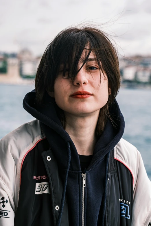 a woman wearing a black jacket by the ocean